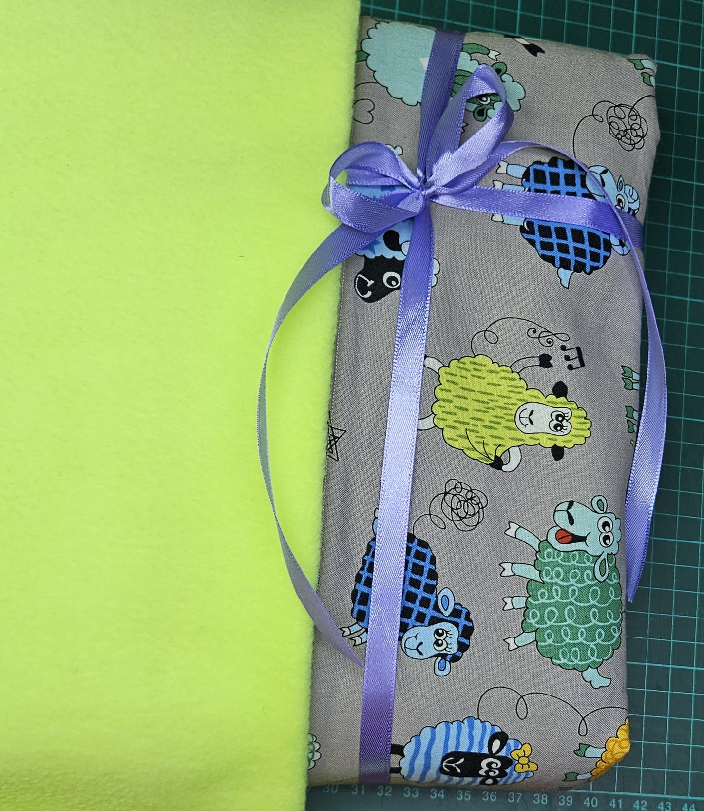 Fun Colourful Sheep's Handmade Blanket on Grey background. Double sided, cotton fabric in one side, and bright fluorescent green fleece at the back.